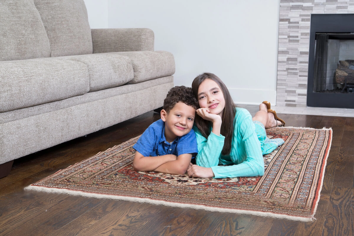Children relaxing on a clean area rug in a living room